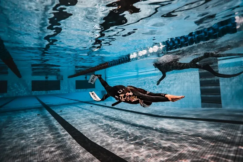 Deux apnéistes nagent en piscine, vue sous l'eau, bleu turquoise