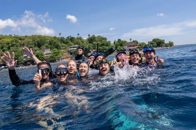Groupe de plongeurs souriants dans l'eau, avec masques et tubas