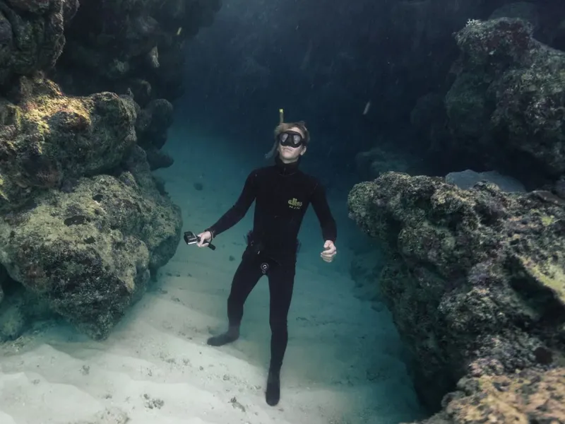 Plongeuse explorant un récif rocheux sous-marin avec une visibilité claire