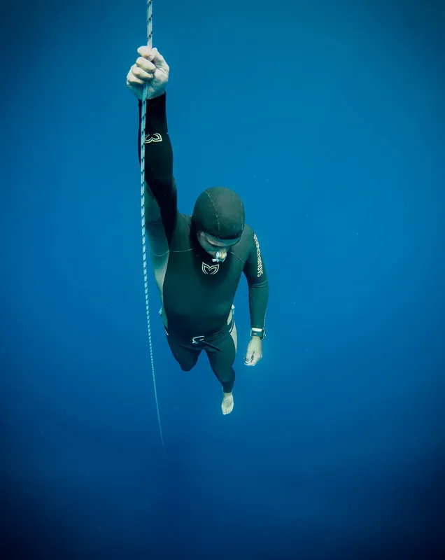 Apnéiste en combinaison noire descendant le long d'un câble vertical
