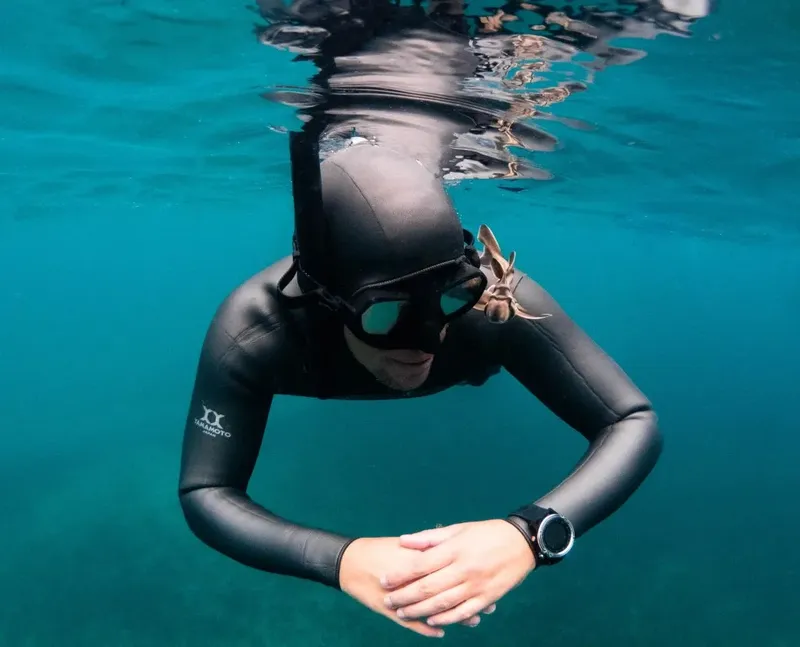 Apnéiste en combinaison noire nageant sous l'eau avec masque et tuba