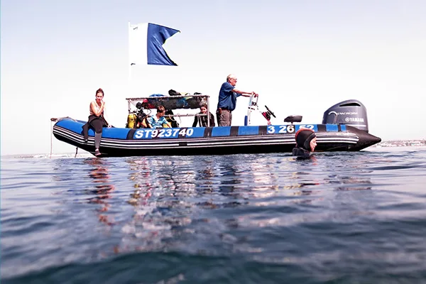 Bateau de plongée avec des plongeurs, une personne sort de l'eau
