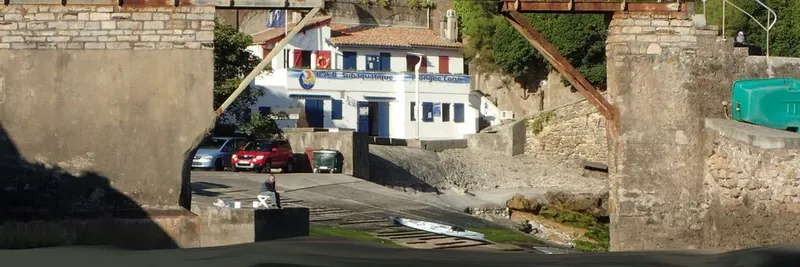 Bâtiment blanc avec des voitures et une personne près d'un accès à l'eau