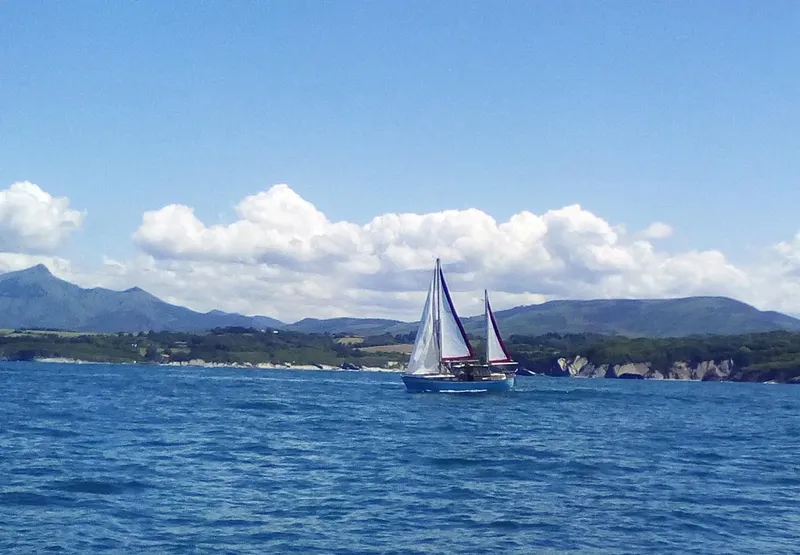 Voilier naviguant sur une mer bleue avec des montagnes en arrière-plan