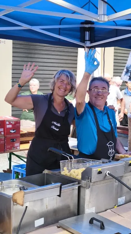 Deux personnes souriantes derrière un comptoir de friture en extérieur