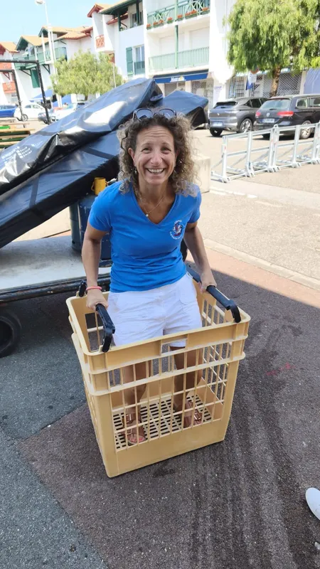 Femme souriante tenant un casier rempli d'équipements de plongée
