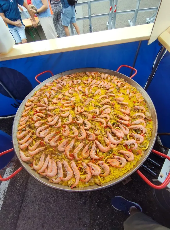 Grande paella aux crevettes servie lors d'un événement en extérieur