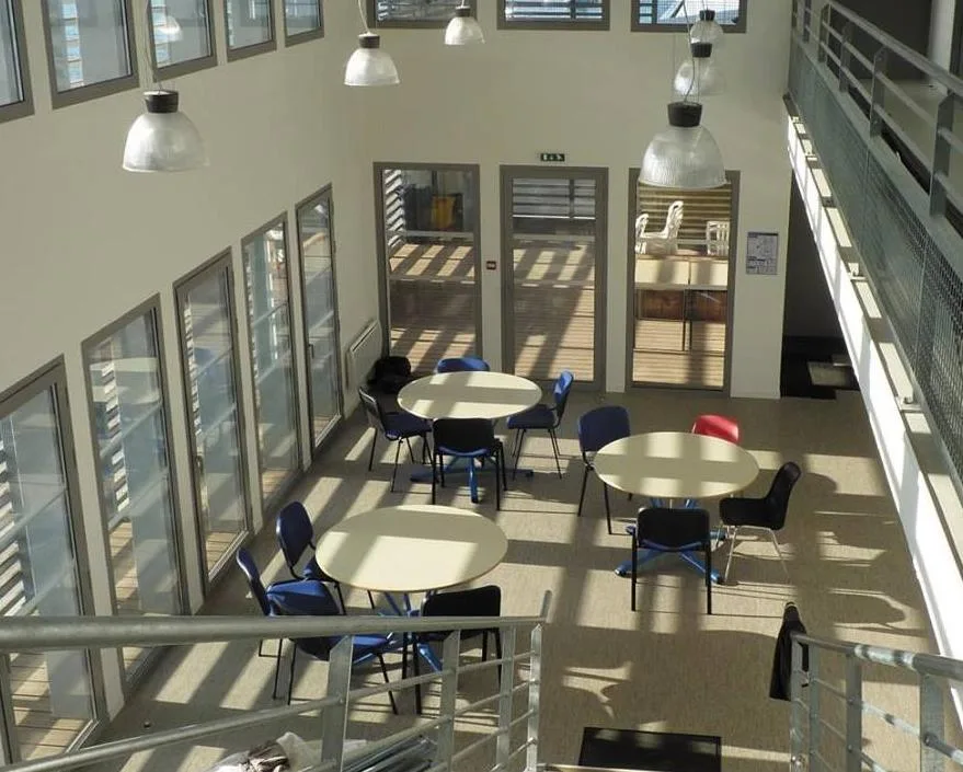 Vue d'une salle de repos avec tables, chaises et éclairage suspendu