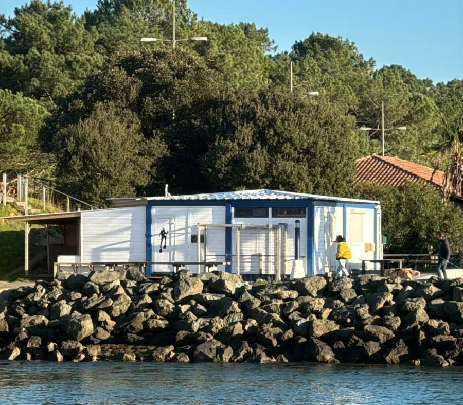 Bâtiment bleu et blanc près de l'eau avec des personnes et rochers