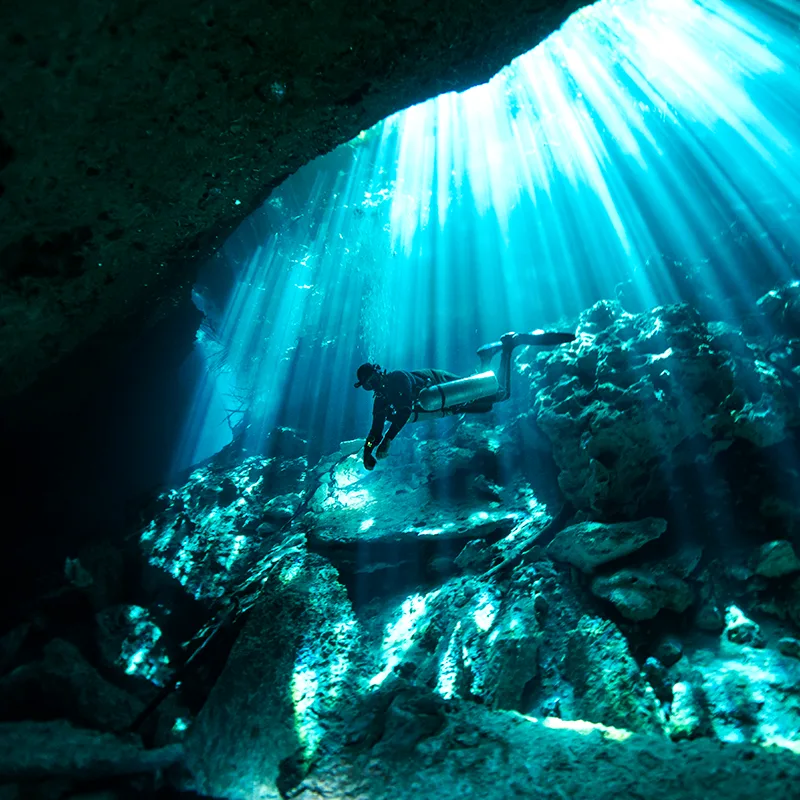 Plongeur explorant une grotte sous-marine éclairée par des rayons de lumière