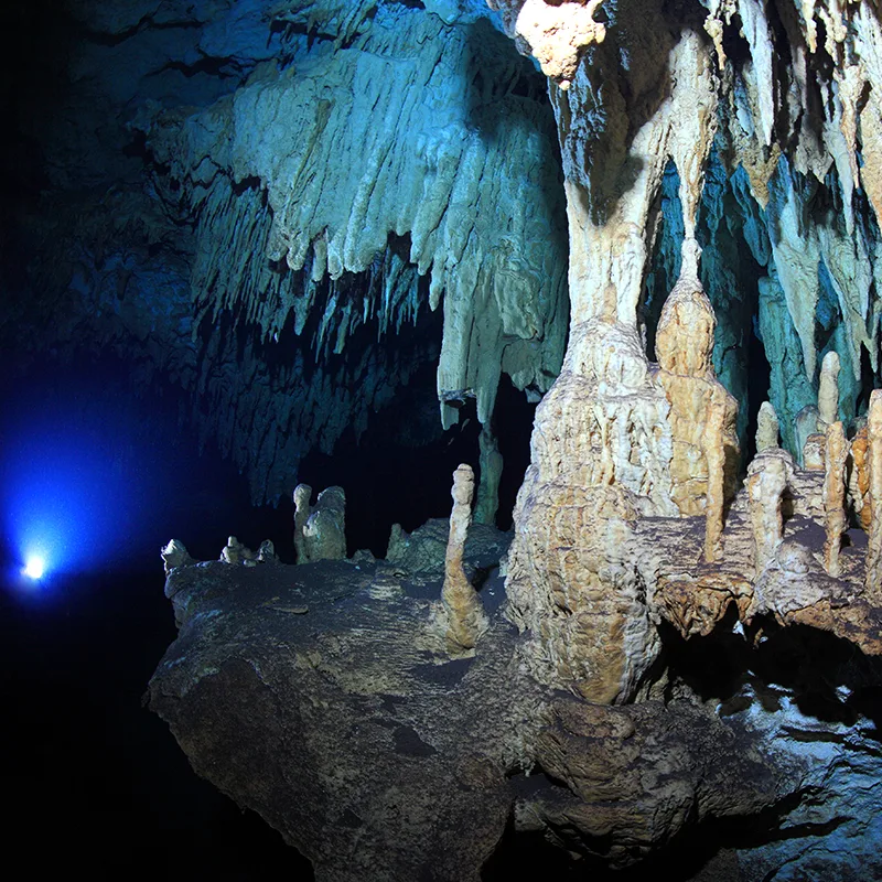 Grotte sous-marine illuminée avec formations rocheuses et stalactites bleues