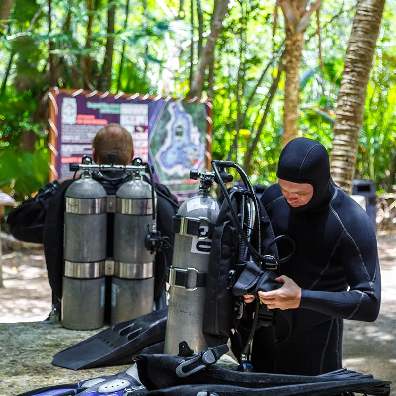 Deux plongeurs équipent leur matériel près de la végétation tropicale