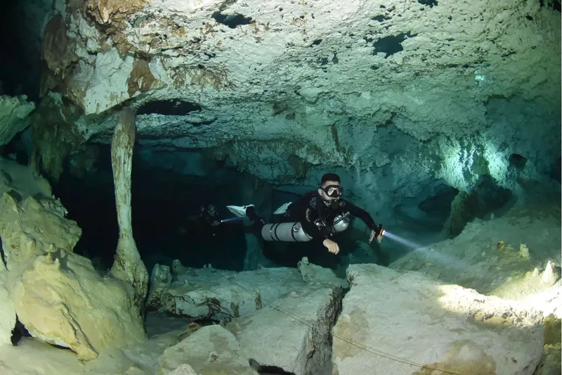 Plongeur explore une grotte sous-marine éclairée par une lampe torche