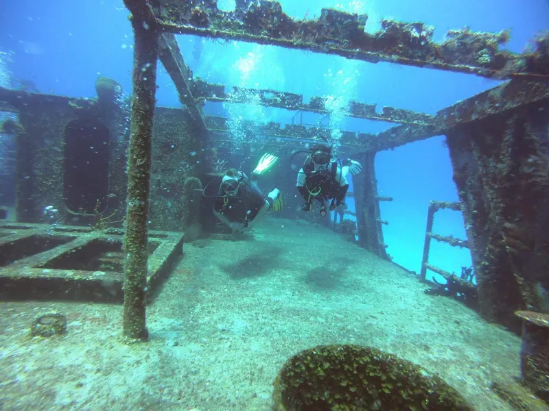Deux plongeurs explorent l'épave d'un navire sous-marin éclairée