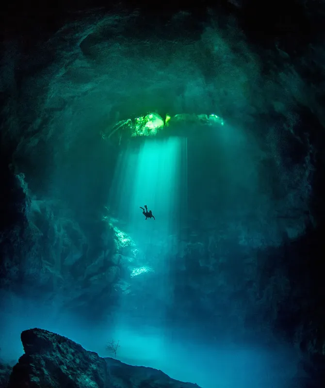 Plongeur solitaire explorant une grotte sous-marine éclairée par le soleil