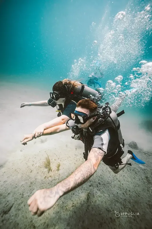 Deux plongeurs explorent les fonds marins, bulles et lumière turquoise