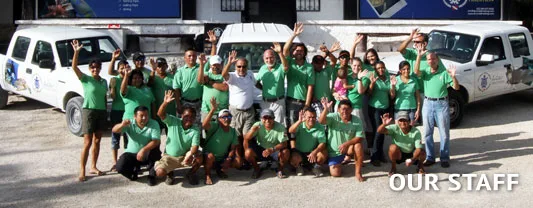 Equipe du centre de plongée souriante posant devant les véhicules et locaux