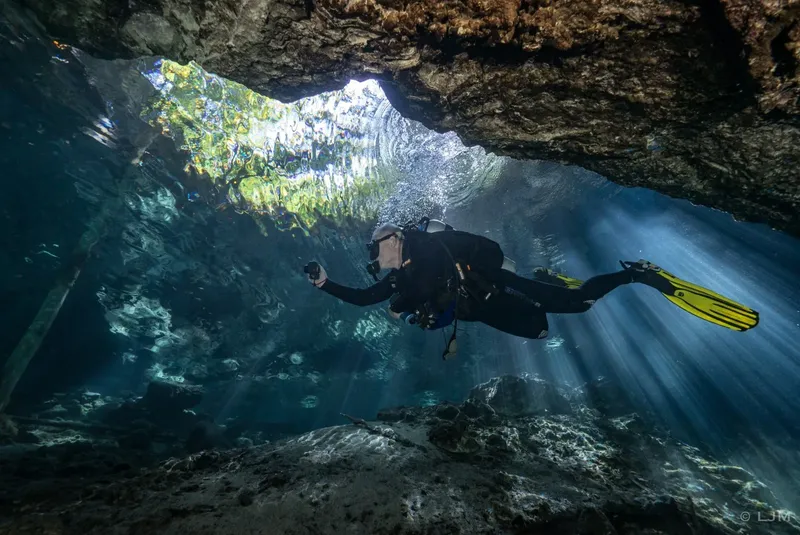 Plongeur explore une grotte sous-marine avec des rayons de lumière
