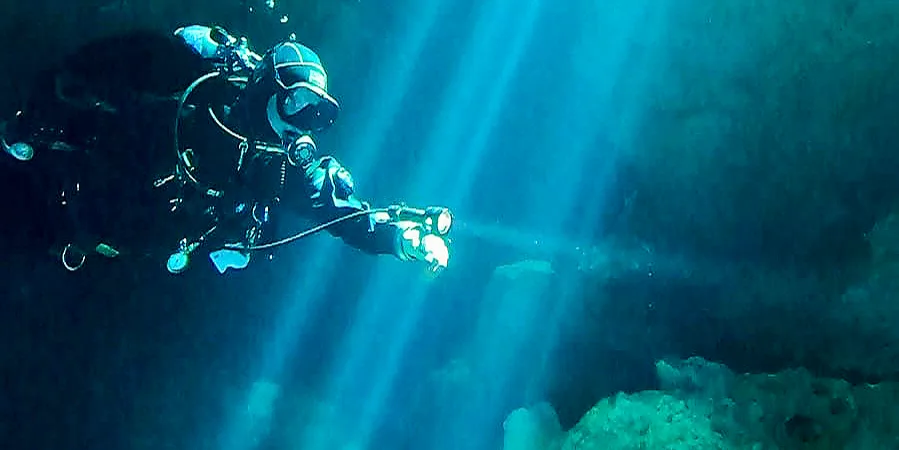 Plongeur explore une grotte sous-marine avec des rayons lumineux