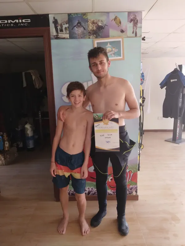 Deux personnes souriantes posent avec un certificat de plongée