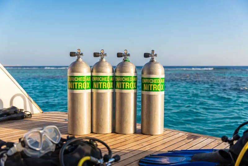 Bouteilles de Nitrox alignées sur un ponton en bois face à la mer