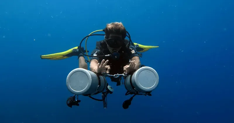 Plongeur en scaphandre autonome nageant dans une eau bleue claire