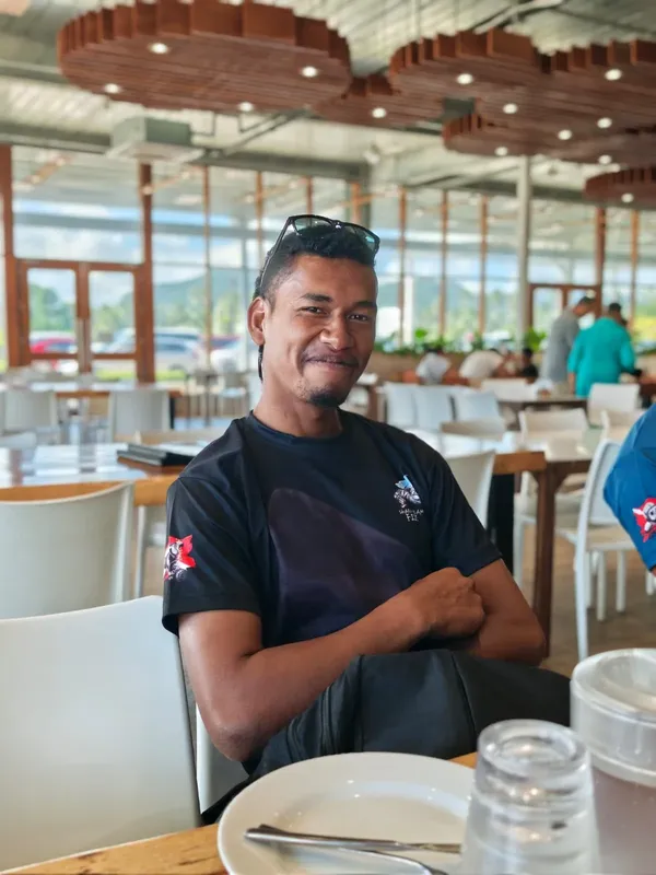 Un homme souriant est assis à une table dans un restaurant lumineux
