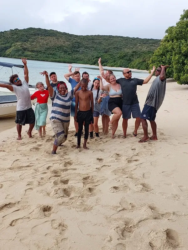 Groupe de personnes souriantes sur une plage ensoleillée avec un bateau