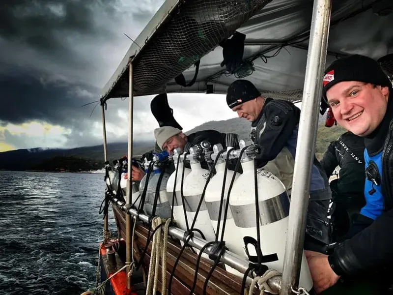 Plongeurs souriants sur un bateau avec des bouteilles et combinaisons