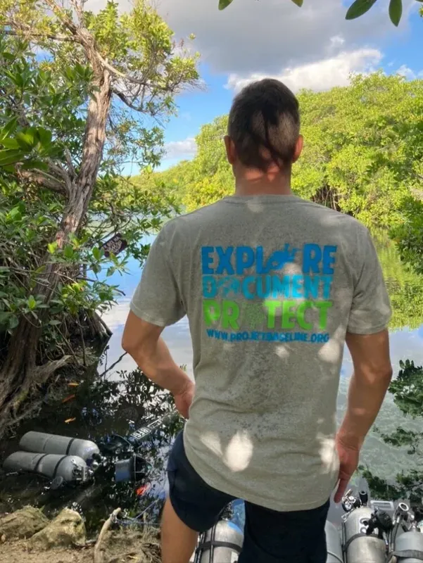Homme de dos regardant la mer avec un t-shirt imprimé