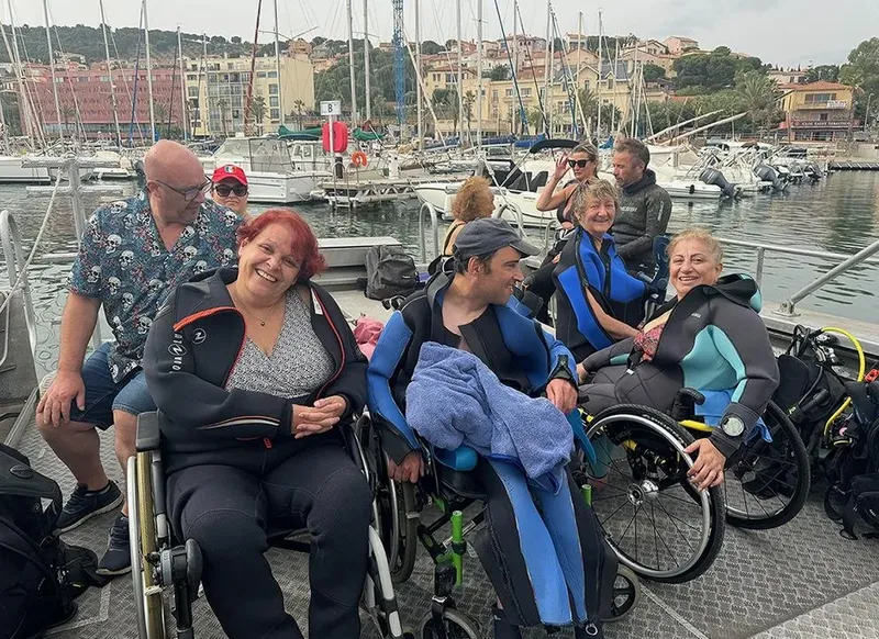 Groupe de personnes en combinaisons de plongée sur un quai ensoleillé