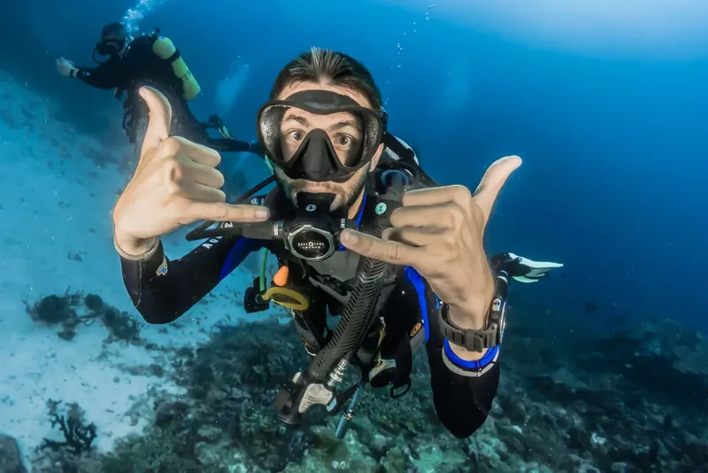 Plongeur souriant avec signe de validation sous l'eau bleu clair