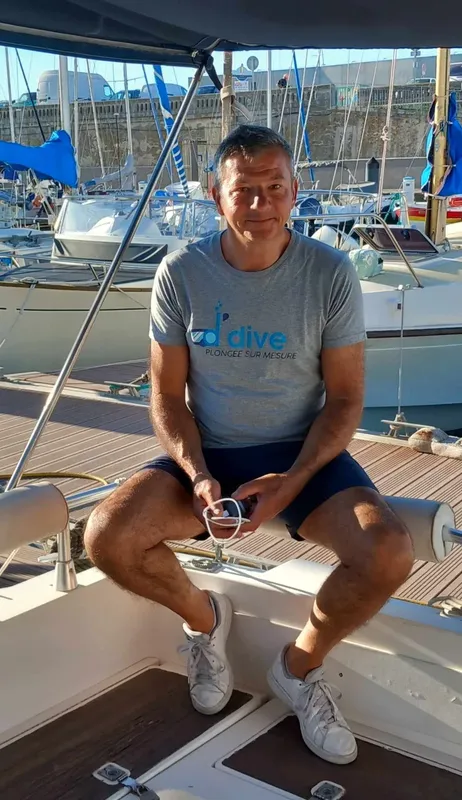 Homme souriant assis sur un bateau de plongée au port