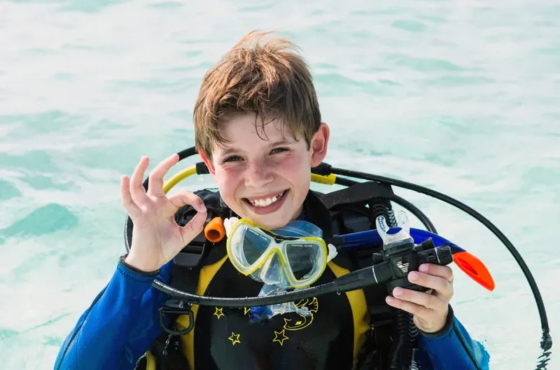Jeune plongeur souriant avec son équipement de plongée en mer