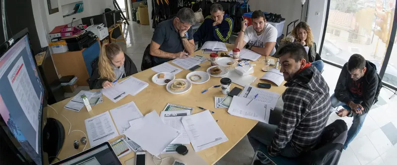 Groupe de personnes assises autour d'une table, en train d'écrire