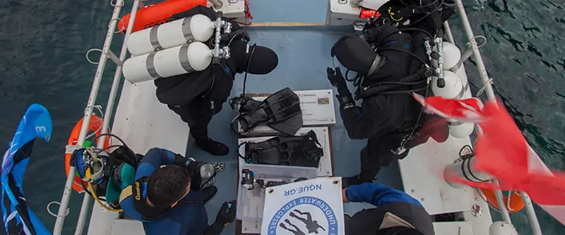 Plongeurs sur un bateau, préparant l'équipement, avec un logo visible