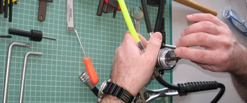 Mains manipulant un detendeur de plongée avec outils et montre