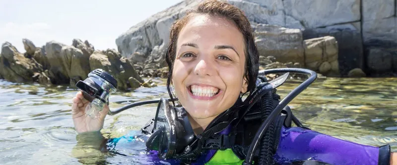 Plongeuse souriante tenant un appareil photo sous-marin en mer