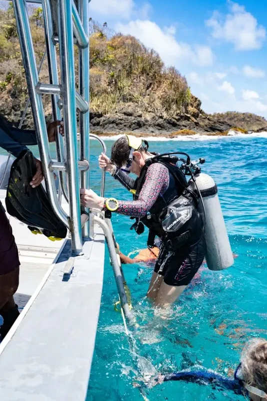 Plongeuse s'équipe sur un bateau, prête à entrer dans l'eau turquoise