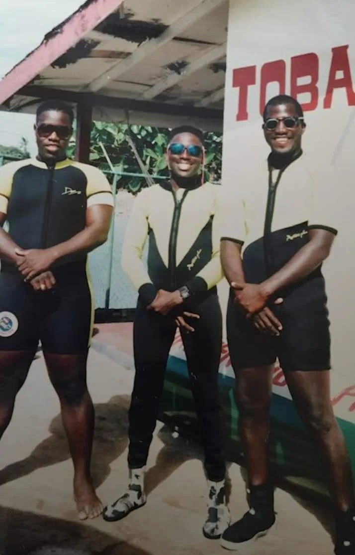 Trois hommes souriants en tenue de plongée, posant ensemble