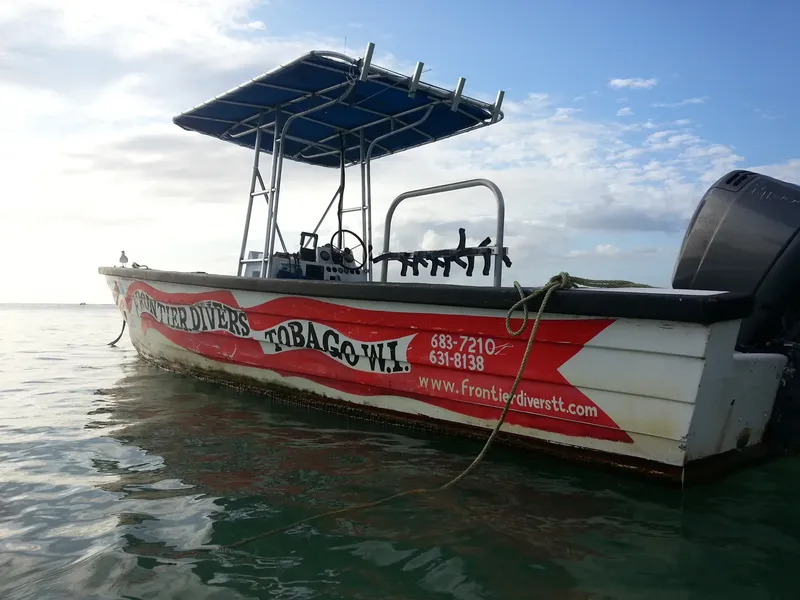 Bateau de plongée blanc et rouge amarré sur une mer calme