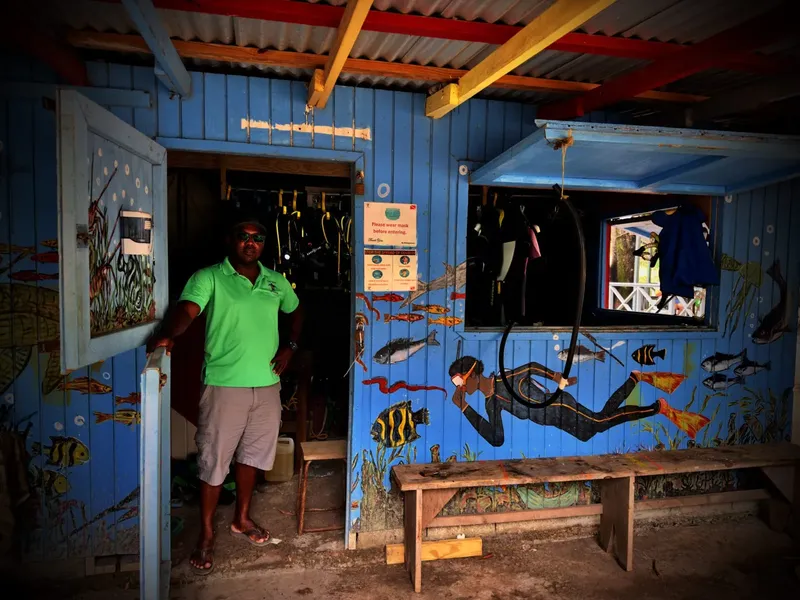 Homme devant un local de plongée décoré de peintures marines et d'équipement