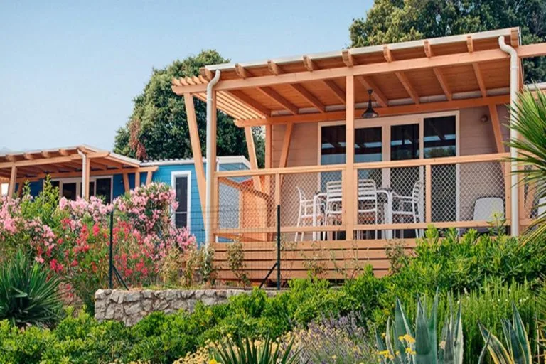 Mobil-homes en bois avec terrasse et végétation luxuriante ensoleillée