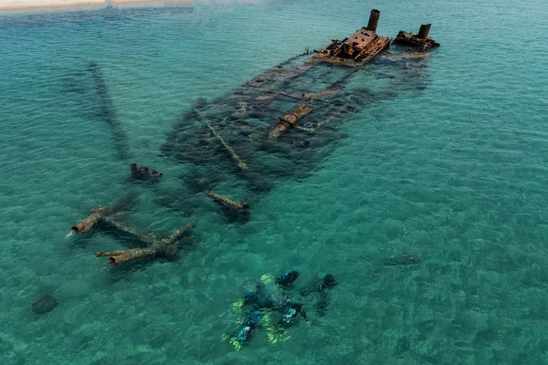 Plongeurs explorent l'épave d'un navire coulé en eau turquoise claire