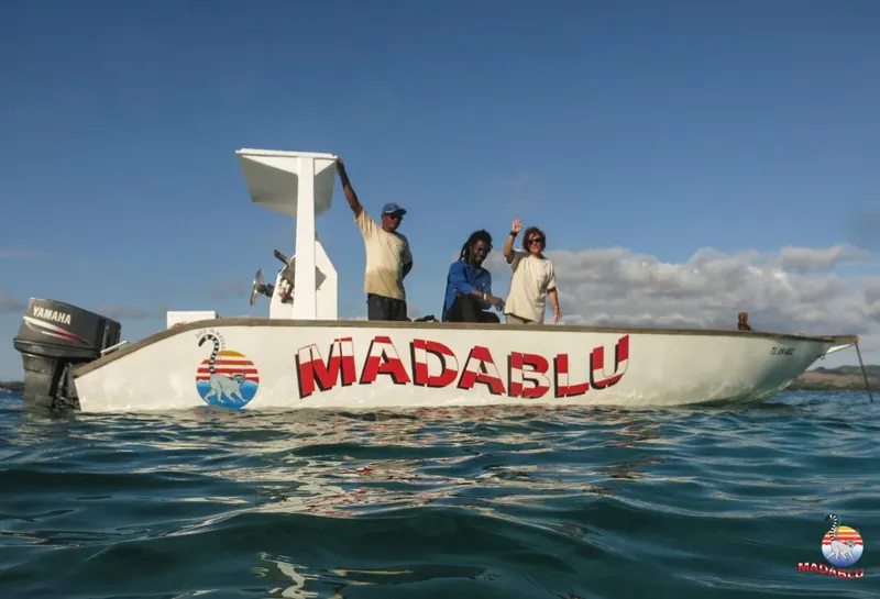 Trois personnes sur un bateau blanc avec le nom MADABLU