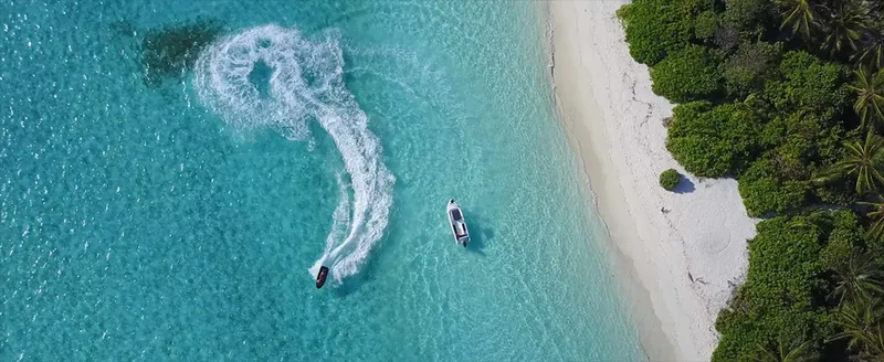 Vue aérienne d'un bateau naviguant dans une eau turquoise et claire