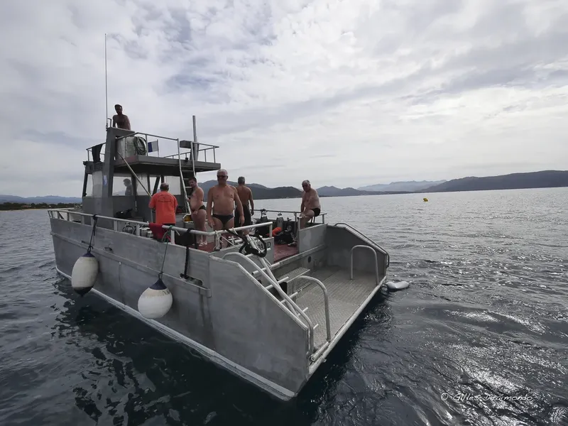 Plongeurs sur un bateau gris en mer, préparation pour une sortie
