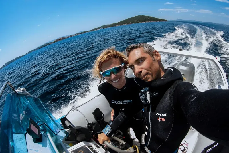 Deux plongeurs souriants à bord d'un bateau semi-rigide en mer