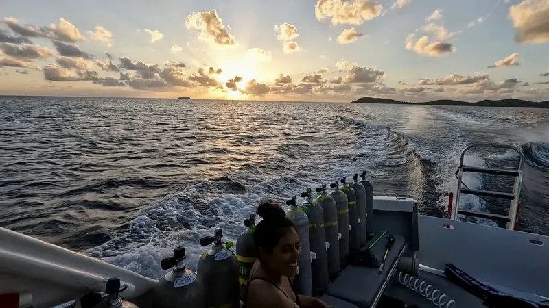 Femme souriante sur un bateau de plongée avec des bouteilles