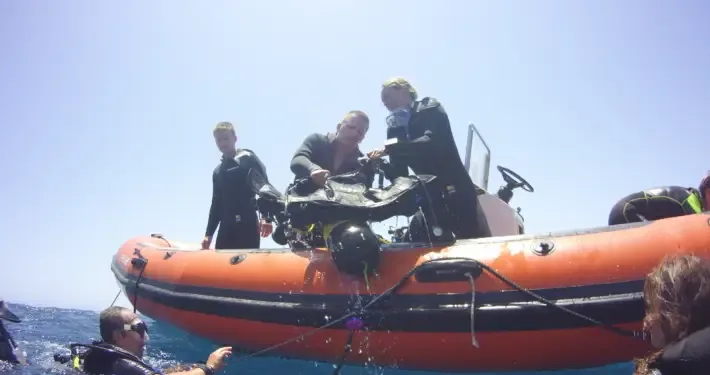 Plongeurs s'équipent sur un bateau orange et noir en mer
